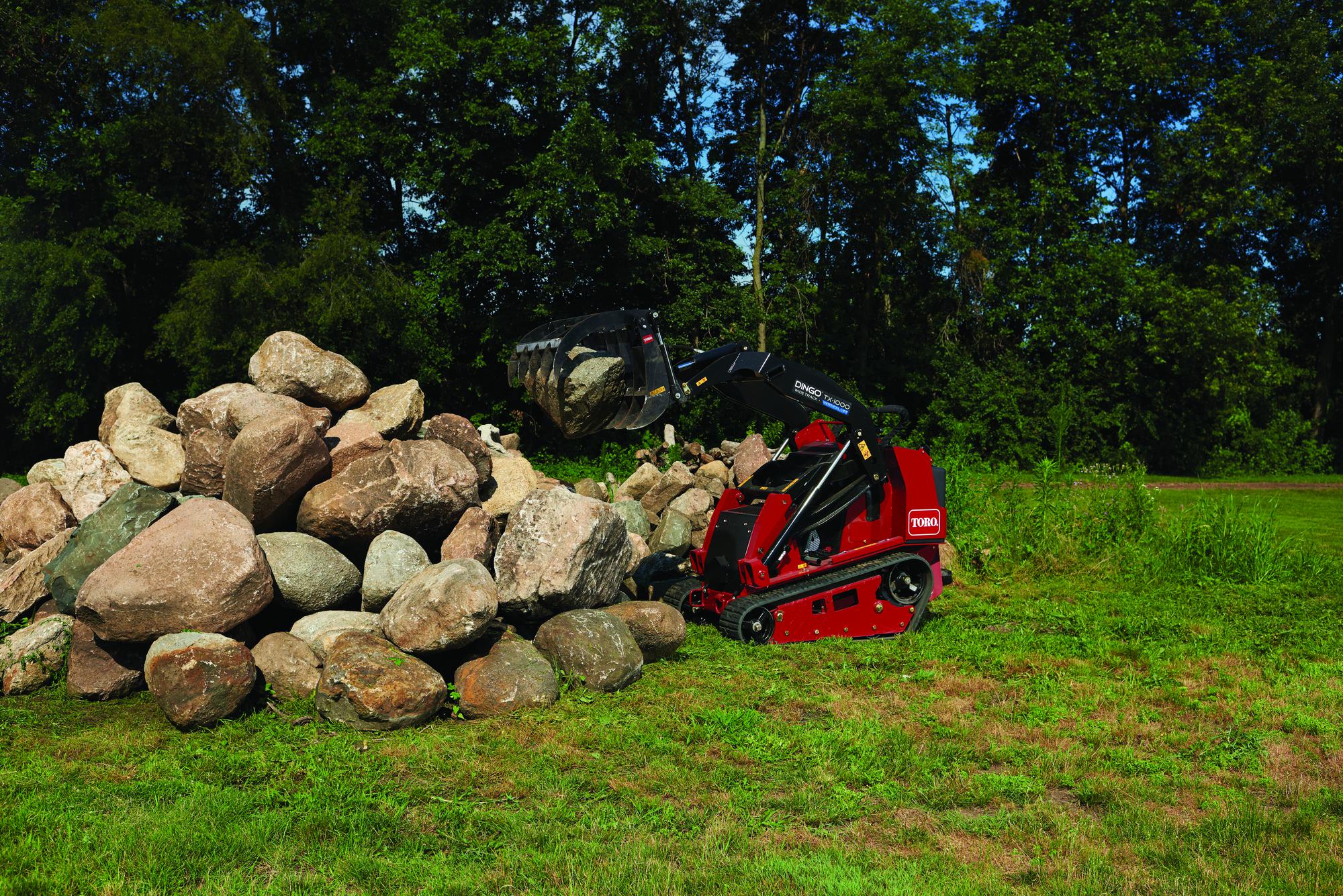 A mini skid steer sitting next to a pile of rocks